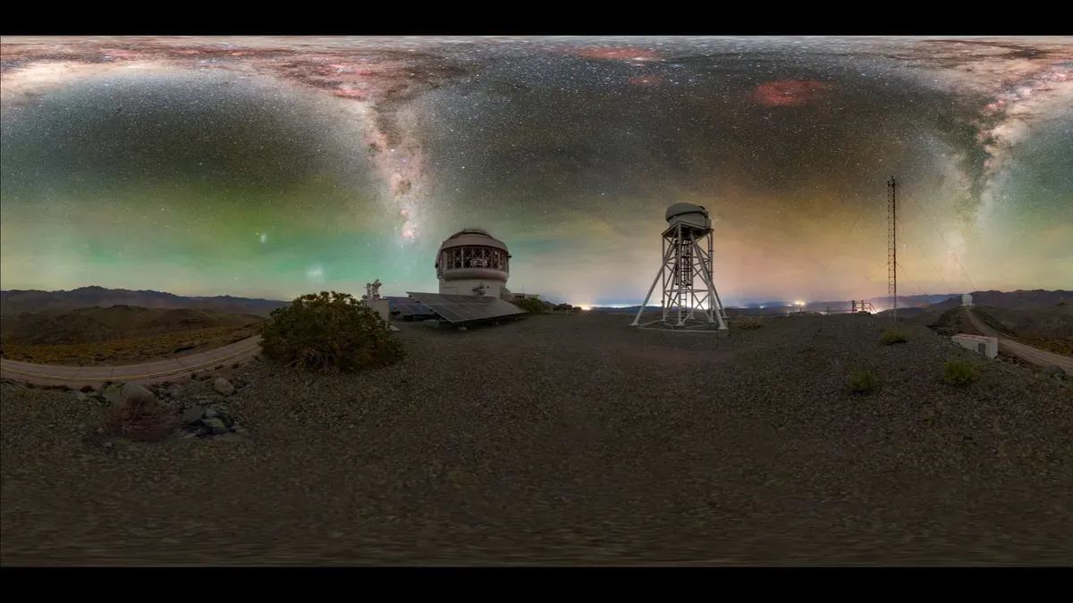 The Milky Way arches above the Gemini South Observatory, with its solar panel array visible in the foreground, captured by photographer Petr Horálek.
