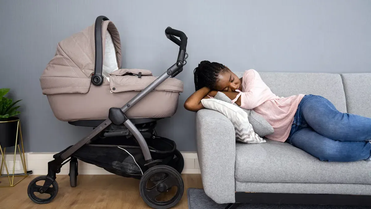 A mother holding her infant while sitting in a chair, with a worried expression